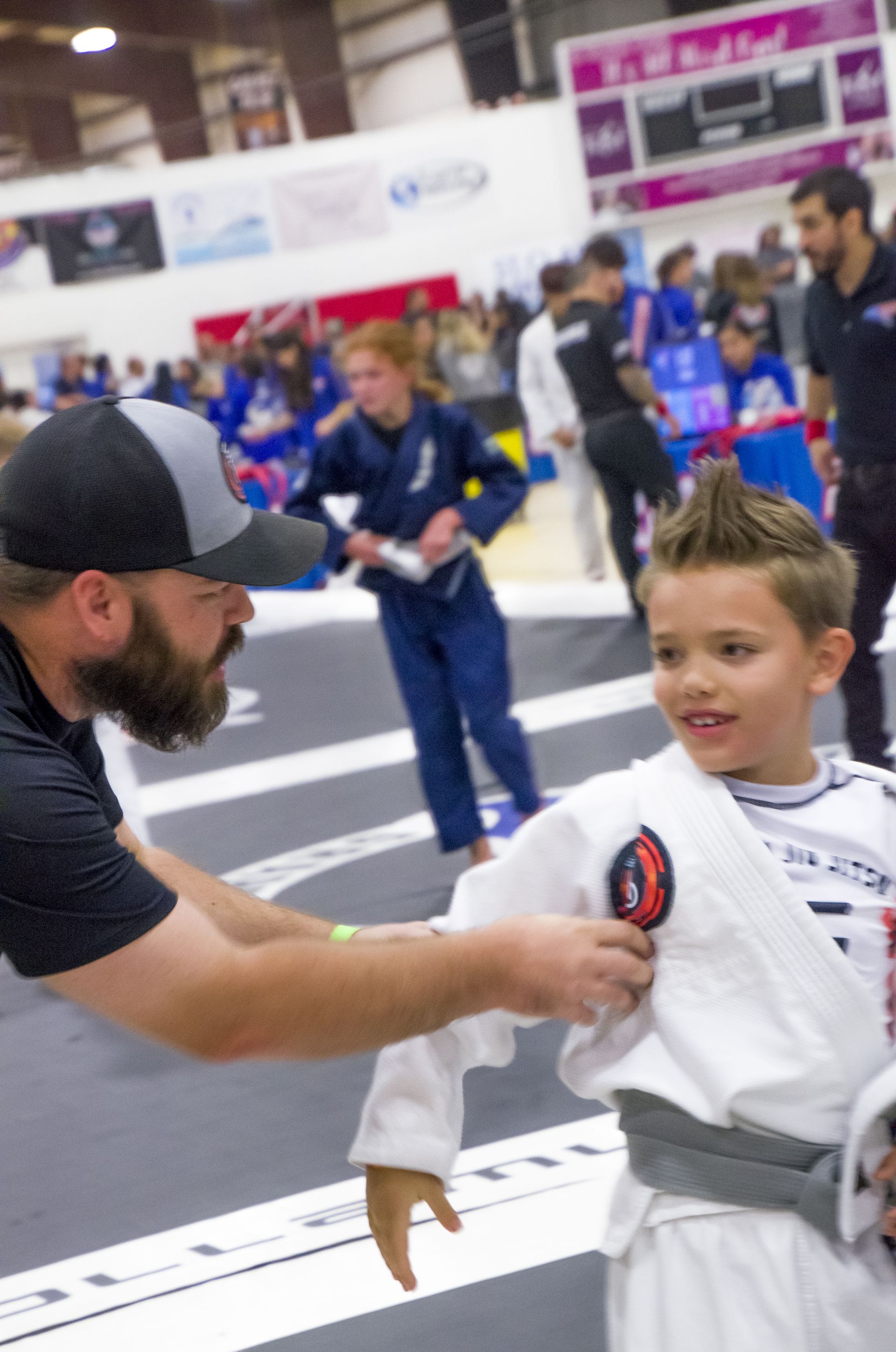 A coach tying a young student's belt before class at Second Grip Jiu Jitsu