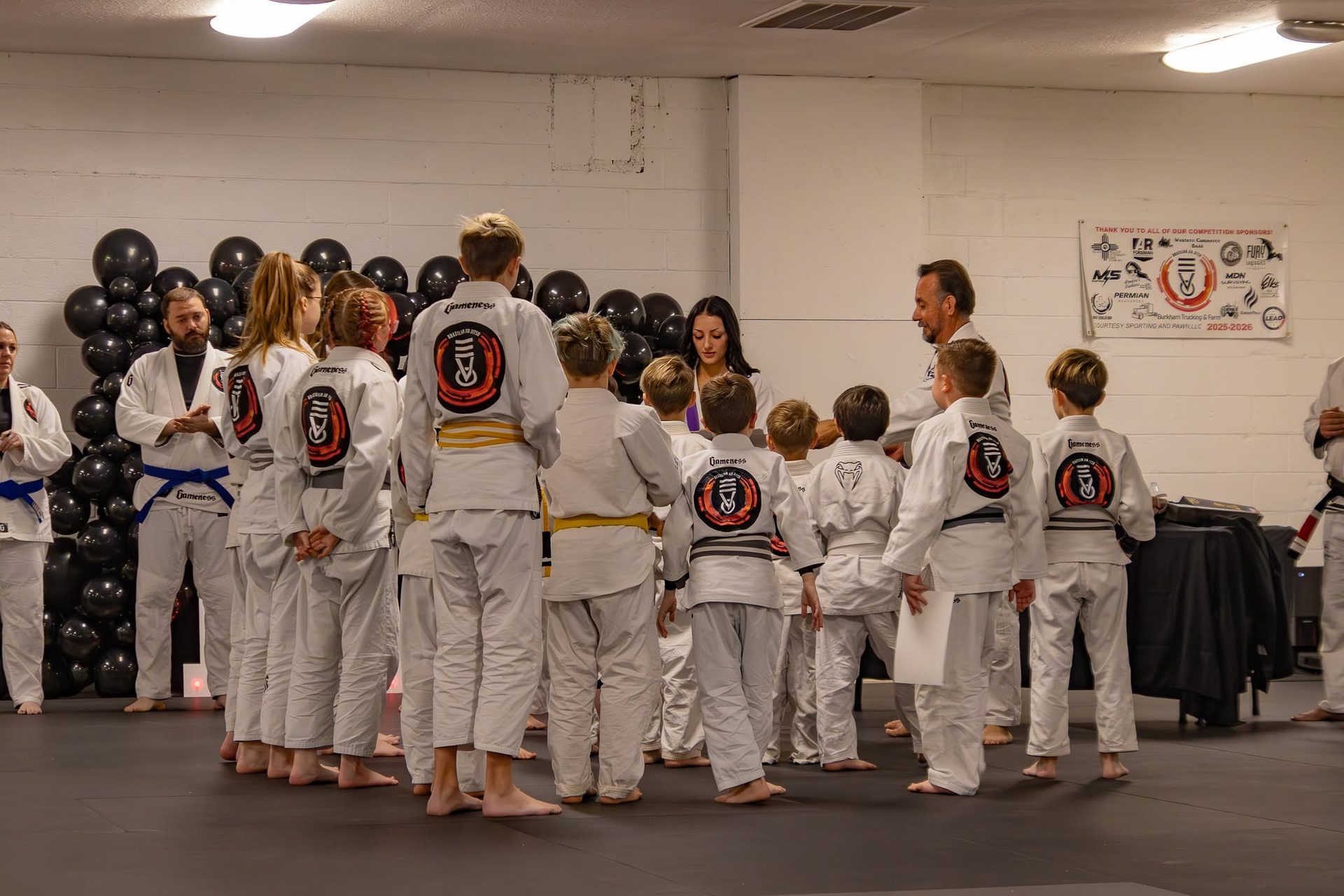 Students lined up in their gis to receive new belts at a Second Grip Jiu Jitsu promotion ceremony in Carlsbad, New Mexico