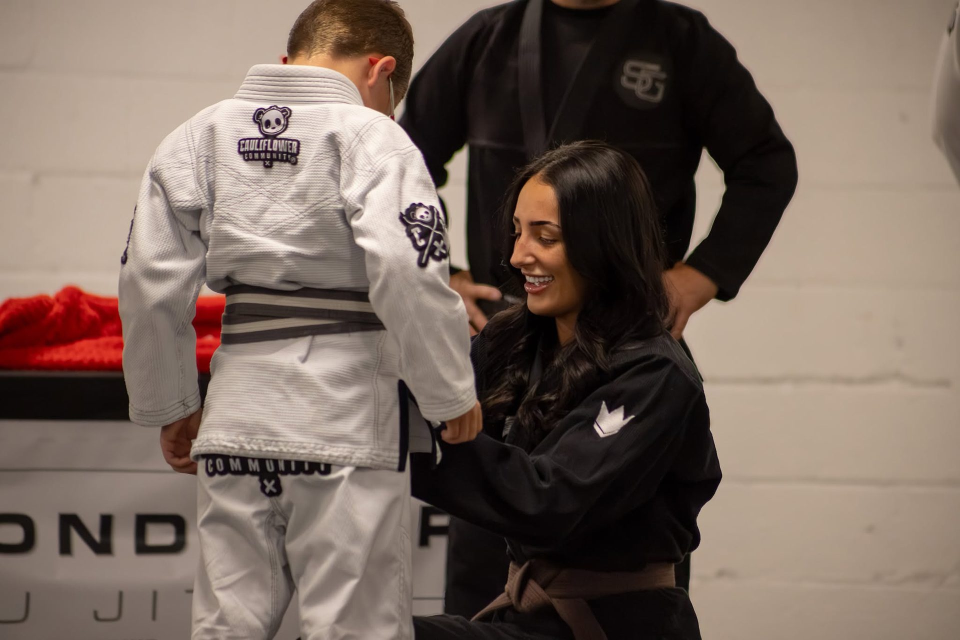 A coach fastening a young student's belt at Second Grip Jiu Jitsu